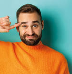 Close-up of man expressing disdain, scolding person, pointing finger at head and looking at camera, standing over light blue background.
